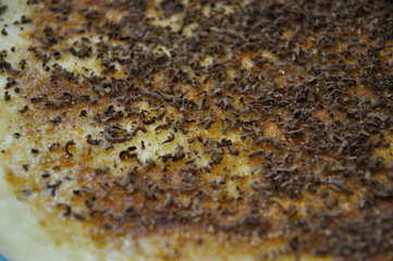 Raw dough layer covered with grated chocolate, white sugar and ground cinnamon before make a roll for Danish buns. Close up.