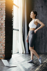 Female sports figure. Asian woman stands in front of laptops to start aerobics classes online.Fitness clubs closed due to pandemic