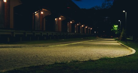 Nocne zdjęcie brukowanej drogi, latarnie i szereg drzwi Białystok, podlaskie, polska, Europa