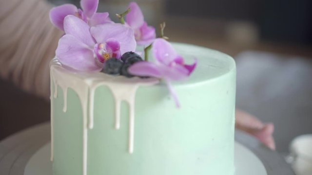 Confectioner neatly decorates turquoise wedding biscuit cake with blueberries