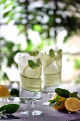 Lime, cucumber, parsley cocktail, lemonade, detox water with ice cubes in a glasses on a white plate. Detox cucumber and mint diet drink, healthy summer cooler.
