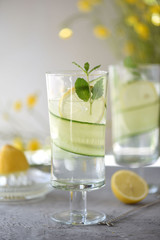 Lime, cucumber, parsley cocktail, lemonade, detox water with ice cubes in a glasses on a white plate. Detox cucumber and mint diet drink, healthy summer cooler.
