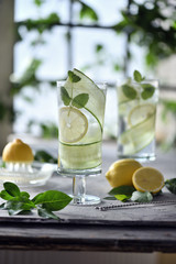 Lime, cucumber, parsley cocktail, lemonade, detox water with ice cubes in a glasses on a white plate. Detox cucumber and mint diet drink, healthy summer cooler.
