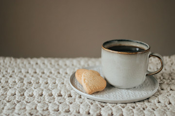 Cozy breakfast, a cup of coffee and cookies on biege knitted blanket with copy space