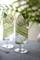 Lime, cucumber, parsley cocktail, lemonade, detox water with ice cubes in a glasses on a white plate. Detox cucumber and mint diet drink, healthy summer cooler.
