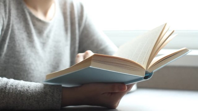 Young woman reading book in living room, turning page, learning, studying, education, read books, stay home concept.