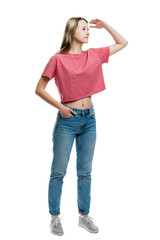 A young girl in jeans and a red T-shirt stands looking into the distance. Full height. Isolated on a white background. Vertical.