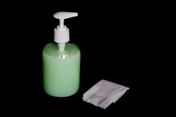 Bottle with detergent and a napkin on a dark background.