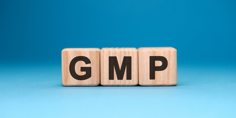 GMP word cube on a blue background. Business concept.