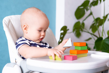 baby game. Little clever caucasian child playing colorful wood toys sitting on highchair. games for early development. New born infant kids leisure.