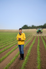 Farmer with tablet in field with tractor in background