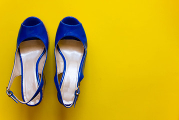above view of female legs with blue summer shoe on yellow background. Free copy space. Concept  of trend and fashion.