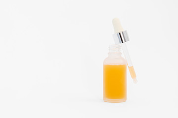 Pipette with collagen moisturizing hyaluron serum with orange liquid in a light matt bottle with pipette isolated on grey background.