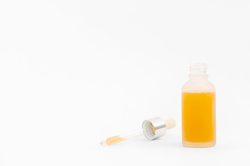 Pipette with collagen moisturizing hyaluron serum with orange liquid in a light matt bottle with pipette isolated on grey background.