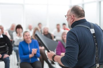 Mature caucasian man gives a speech in meeting in modern open office