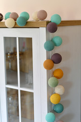 Cotton light balls in pastel colours on the cupboard as a creative decoration in home interior. 
