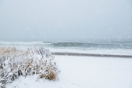 Ocean waves on snowy covered beach in winter