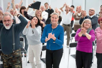 Audience applaud with raised hands in the meeting