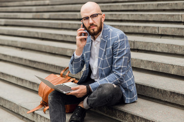  businessman sits on the sucks and talking on a cell phone