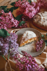 Homemade Apple pie on a wooden table next to a bowl of lilacs. Gentle toning.