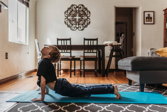 School-age boy doing yoga in living room during isolation