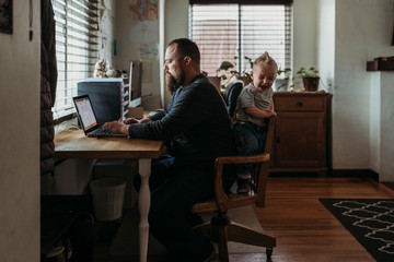 Boy crying while his father working from home on laptop