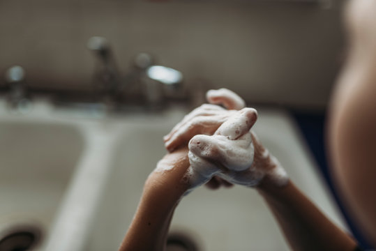 Close up of young hands being washed with soap