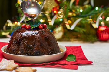 Burning christmas pudding on decorated fir tree background