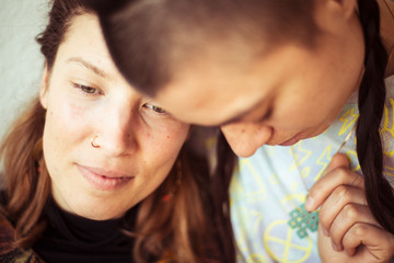 Same sex lesbian couple stay at home and cuddle in warm light