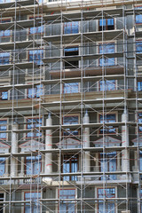 scaffolding at the facade of a building under construction, multi-storey building, without people