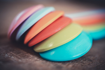 Close up of pilling of colorful plastic spoons. Teaspoon are laying on a wooden table