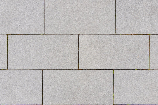 Close up small tiny stone pebble in concrete block tile with running bond pattern floor texture background