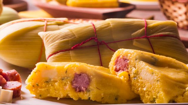 Slide shot Salty Pamonha with sausage and cheese - typical food of green corn - tasty and cheap - typical and popular street food with smoke.