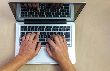 male hands on laptop isolated on khaki background