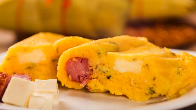 Slide shot Salty Pamonha with sausage and cheese - typical food of green corn - tasty and cheap - typical and popular street food with smoke.