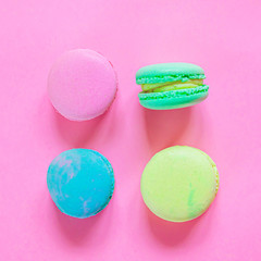 Sweet almond colorful pink blue yellow green macaron or macaroon dessert cake isolated on trendy pink pastel background. French sweet cookie. Minimal food bakery concept. Flat lay top view, copy space