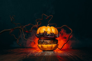 Burger Halloween. halloween concept of a burger with big beef patties with pumpkin head rolls for...