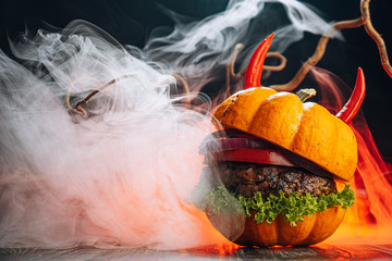 Burger Halloween. halloween concept of a burger with big beef patties with pumpkin head rolls for...