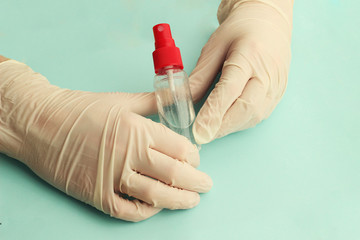 Doctor’s hands in white medical gloves on the table with antibacterial antiseptic. Sanitizer for...