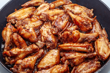 lots of fried chicken wings in a pan. close up