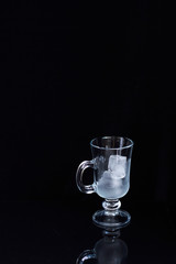 Empty latte glass filled with ice on black background, ice drink concept