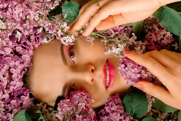 Portrait of a beautiful girl with bright makeup on her eyes and lips. Bouquet lilac around the face, spring girl, flowers in her hair.