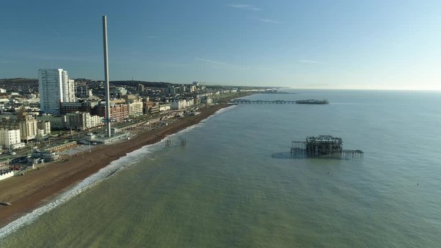 Brighton West Pier, British Airways i360 viewing tower beginning rise up to top and Brighton Palace Pier all framed with calm sea and glorious sunshine