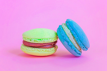 Sweet almond colorful unicorn blue yellow macaron or macaroon dessert cake isolated on trendy pink pastel background. French sweet cookie. Minimal food bakery concept Copy space
