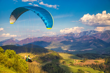 Flying paraglider from the Stranik hill over the mountainous landscape of the Zilina basin in the...
