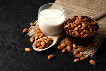 glass of almond milk without lactose and sugar with sprinkled nuts, a veggie milk drink on a black table
