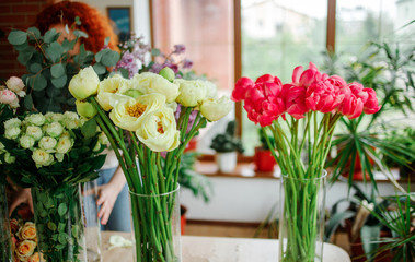 Florist at work: pretty young redhair woman making fashion modern bouquet of different flowers