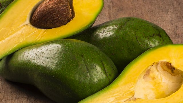 Three avocados and a half over a table.