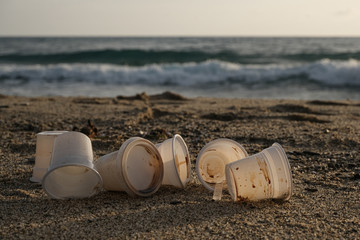 Disposable plastic dirty coffee cups discharged waste,throw pollution on sea shore