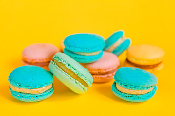 Sweet almond colorful unicorn pink blue yellow green macaron or macaroon dessert cake isolated on trendy yellow modern fashion background. French sweet cookie. Minimal food bakery concept Copy space